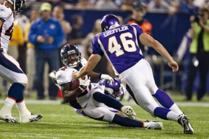 Alphonso Smith - Ein Spieler der Denver Broncos wird während eines Footballspiels von einem ehemaligen Spieler der Minnesota Vikings mit der Trikotnummer 46 zu Boden gebracht. Alt-Text wurde KI-generiert.