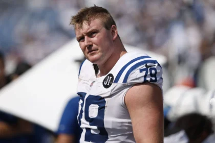Der Footballspieler Bernhard Raimann, der ein weißes Trikot der Indianapolis Colts mit der Nummer 79 trägt, steht auf dem Spielfeld und blickt in die Kamera – ein aufstrebender NFL-Star, der als potenzieller „100-Millionen-Leader“ gilt. Alt-Text wurde KI-generiert.