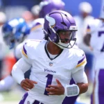 Der Quarterback der Minnesota Vikings in weiß-lila Trikot blickt während eines Footballspiels nach links, im Hintergrund sind Teamkollegen und Gegner zu sehen, während die Nachricht bekannt wird, dass Kyler Murray die Vikings verlässt. Alt-Text wurde KI-generiert.