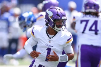 Der Quarterback der Minnesota Vikings in weiß-lila Trikot blickt während eines Footballspiels nach links, im Hintergrund sind Teamkollegen und Gegner zu sehen, während die Nachricht bekannt wird, dass Kyler Murray die Vikings verlässt. Alt-Text wurde KI-generiert.