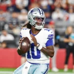 Ein Footballspieler der Dallas Cowboys in Spielkleidung bereitet sich während eines Spiels auf einen Pass vor, während Berichte auftauchen, wonach die Cowboys Joe Milton entlassen haben. Alt-Text wurde KI-generiert.