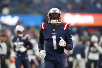 Ein Footballspieler der New England Patriots mit der Rückennummer 1 joggt während eines Spiels über das Spielfeld, kurz nachdem bekannt gegeben wurde, dass Brown die Patriots verlässt. Alt-Text wurde KI-generiert.