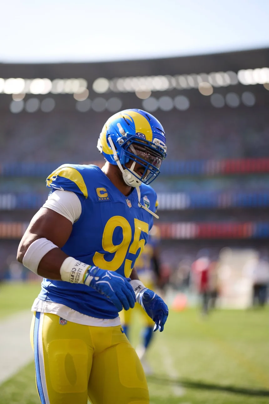 Myles Garrett - Ein Footballspieler in blau-gelbem Trikot und Helm steht während eines Spiels auf dem Spielfeld; im Hintergrund sind das Stadion und die Zuschauer zu sehen. Bericht Garrett wird am Knie behandelt, während er sich auf das nächste Spiel vorbereitet. Alt-Text wurde KI-generiert.