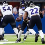 Lamar Jackson - Ein Quarterback im American Football übergibt den Ball während eines Spielzugs an einen Runningback, während im Hintergrund auf dem Spielfeld die Offensive Linemen die Verteidiger blocken – ein Bild, das die Intensität widerspiegelt, die man oft bei den Sonntagsspielen der ersten Woche der NFL sieht, und das Fans und Trainern gleichermaßen erste Erkenntnisse liefert. Alt-Text wurde KI-generiert.