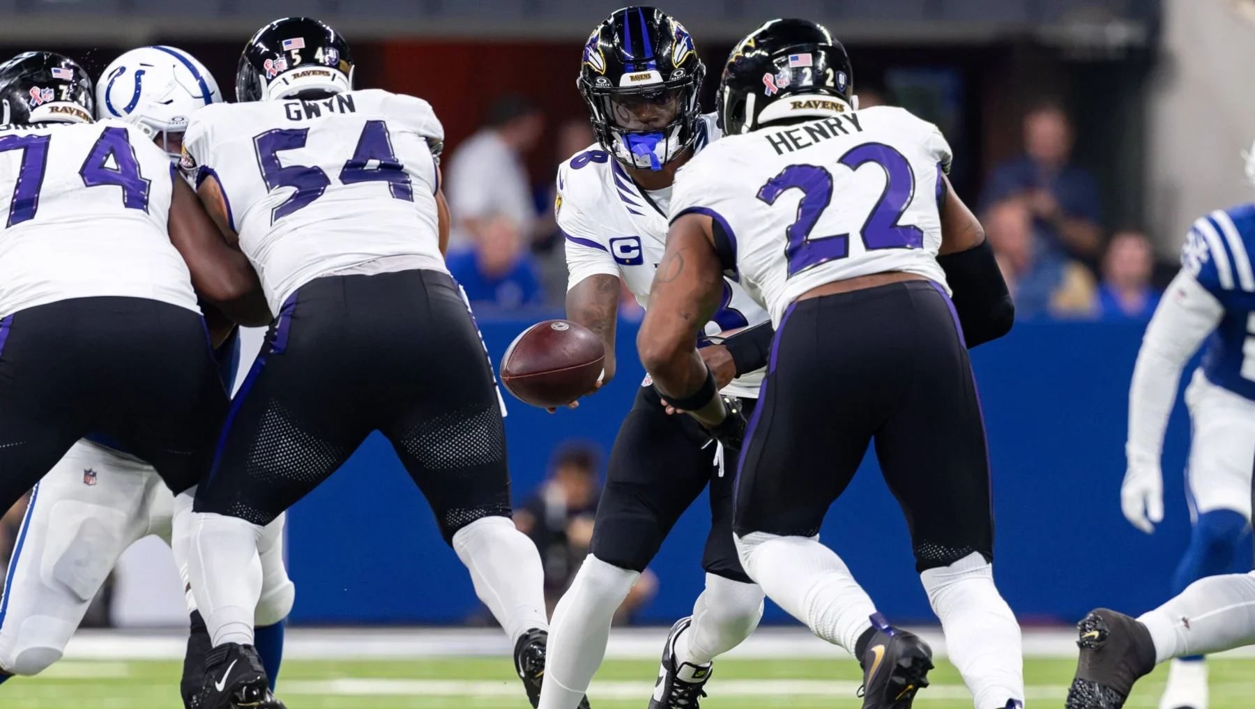 NFL Woche 3 - Lamar Jackson - Ein Quarterback im American Football übergibt den Ball während eines Spielzugs an einen Runningback, während im Hintergrund auf dem Spielfeld die Offensive Linemen die Verteidiger blocken – ein Bild, das die Intensität widerspiegelt, die man oft bei den Sonntagsspielen der ersten Woche der NFL sieht, und das Fans und Trainern gleichermaßen erste Erkenntnisse liefert. Alt-Text wurde KI-generiert.