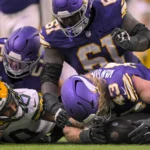 Offensive Line - Vier Footballspieler kämpfen während eines Spiels zwischen den Minnesota Vikings und den Green Bay Packers auf dem Spielfeld um einen freien Ball, während die Packers in diesem intensiven Duell der Rivalen nach Antworten suchen. Alt-Text wurde KI-generiert.
