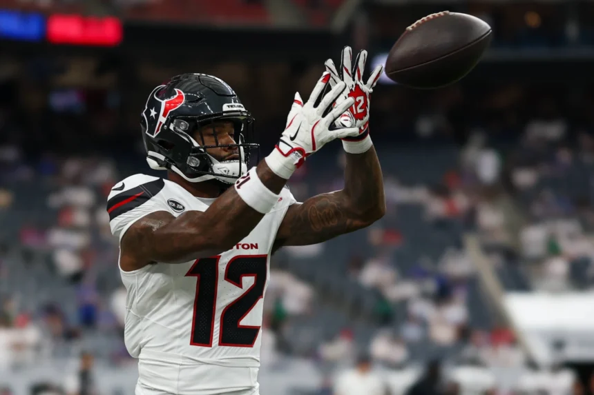 Nico Collins - Ein Footballspieler in einem weißen Trikot der Houston Texans mit der Nummer 12 fängt während eines Spiels einen Football, im Hintergrund sind verschwommene Stadionplätze zu sehen – dies unterstreicht den Moment, in dem Collins von den Texans gegen die Bengals ausfällt. Alt-Text wurde KI-generiert.
