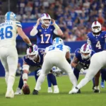 Josh Allen, der Quarterback der Buffalo Bills, erzielt 5 Touchdowns, während er sich darauf vorbereitet, den Snap zu empfangen, und dabei den Verteidigern der Carolina Panthers gegenübersteht. Alt-Text wurde KI-generiert.