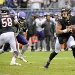 Tyson Bagent, Quarterback der Chicago Bears, bereitet sich auf einen Wurf vor, während seine Teamkollegen die Verteidiger der Minnesota Vikings während eines NFL-Spiels auf einem regennassen Spielfeld blocken – genau wie der Bericht über Bagent vom Montag seine Gelassenheit unter Druck hervorhob. Alt-Text wurde KI-generiert.
