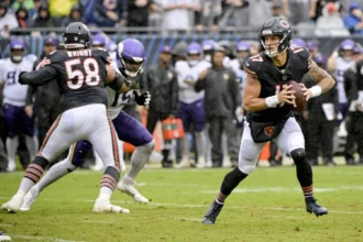Tyson Bagent, Quarterback der Chicago Bears, bereitet sich auf einen Wurf vor, während seine Teamkollegen die Verteidiger der Minnesota Vikings während eines NFL-Spiels auf einem regennassen Spielfeld blocken – genau wie der Bericht über Bagent vom Montag seine Gelassenheit unter Druck hervorhob. Alt-Text wurde KI-generiert.