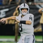 NFL Week 3 - Kirk Cousins - Ein Footballspieler im weißen Trikot der Las Vegas Raiders bereitet sich während eines Spiels der dritten NFL-Runde auf einen Pass vor, im Hintergrund sind Fotografen und Fans zu sehen – sie halten einige der wichtigsten Erkenntnisse dieses Sonntagsspiels fest. Alt-Text wurde KI-generiert.