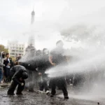 Auf einem öffentlichen Platz in der Nähe des Eiffelturms in Paris werden Menschen mit Wasser besprüht.