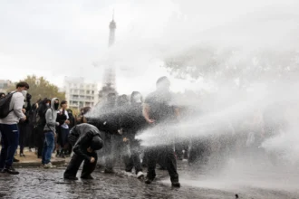 Auf einem öffentlichen Platz in der Nähe des Eiffelturms in Paris werden Menschen mit Wasser besprüht.