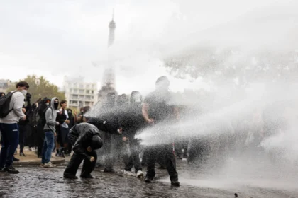 Auf einem öffentlichen Platz in der Nähe des Eiffelturms in Paris werden Menschen mit Wasser besprüht.