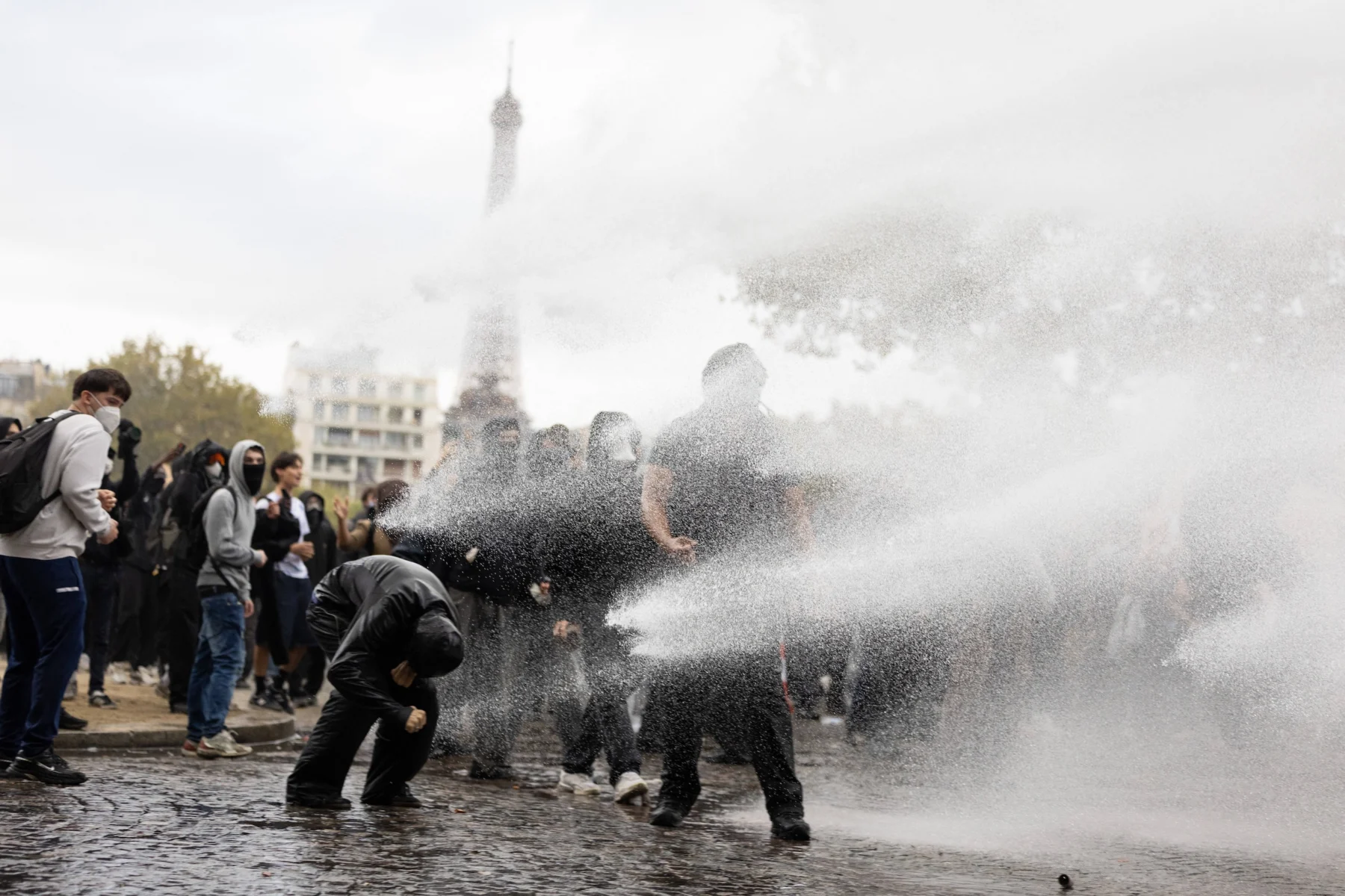 Auf einem öffentlichen Platz in der Nähe des Eiffelturms in Paris werden Menschen mit Wasser besprüht.