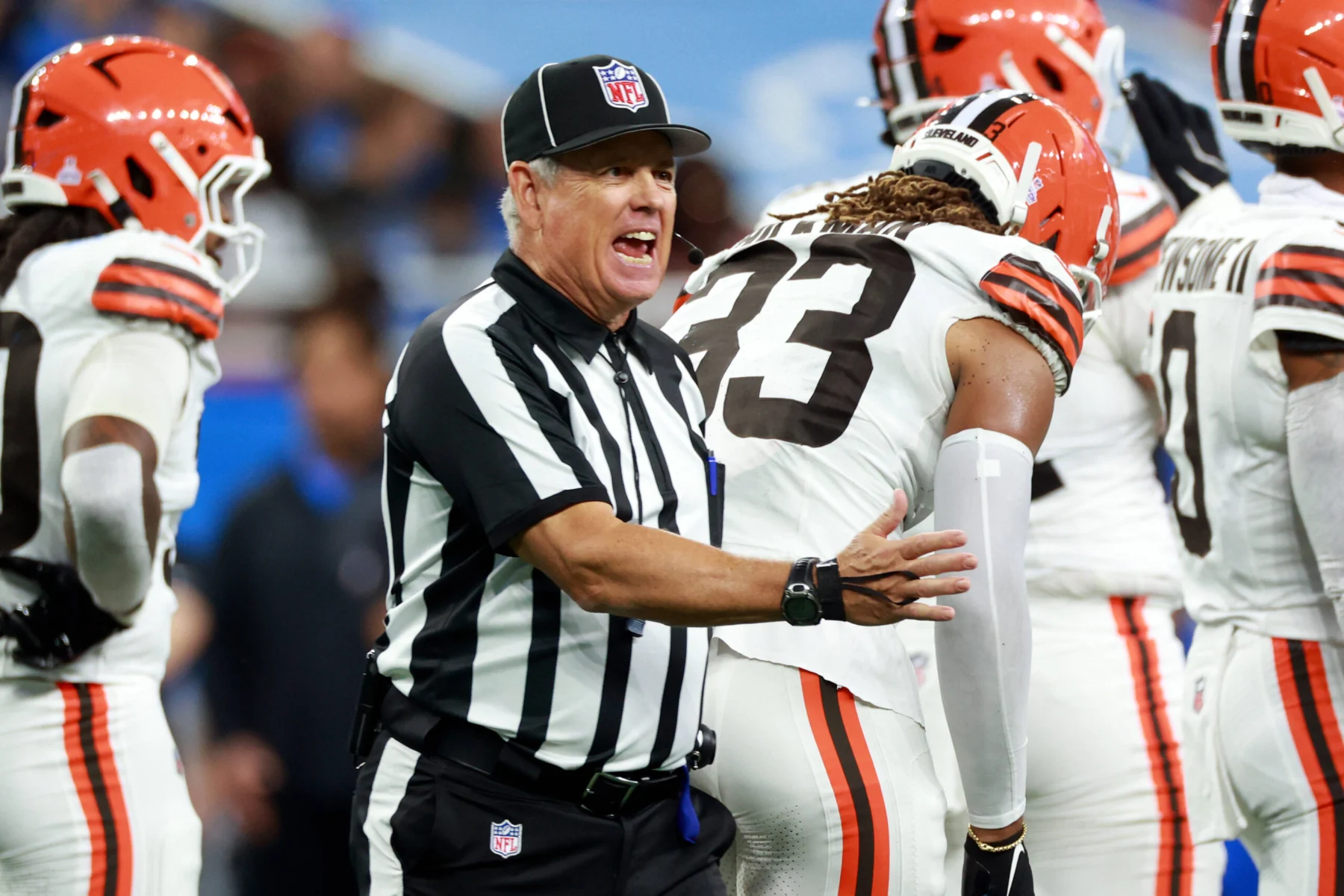 Ein NFL Schiedsrichter, einer von zwei kürzlich suspendierten Offiziellen, gestikuliert, während er auf dem Spielfeld mit einem Spieler der Cleveland Browns spricht. Alt-Text wurde KI-generiert.