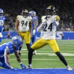 Joey Porter Jr. feiert in der Endzone, während ein Verteidiger der Detroit Lions während eines Footballspiels auf dem Rasen kniet. Alt-Text wurde KI-generiert.
