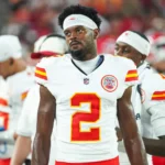 Tyquan Thornton, Wide Receiver der Chiefs, steht während eines Spiels in einem weißen Trikot der Kansas City Chiefs mit der Nummer 2 an der Seitenlinie, im Hintergrund sind seine Teamkollegen und die Stadionbeleuchtung zu sehen. Alt-Text wurde KI-generiert.