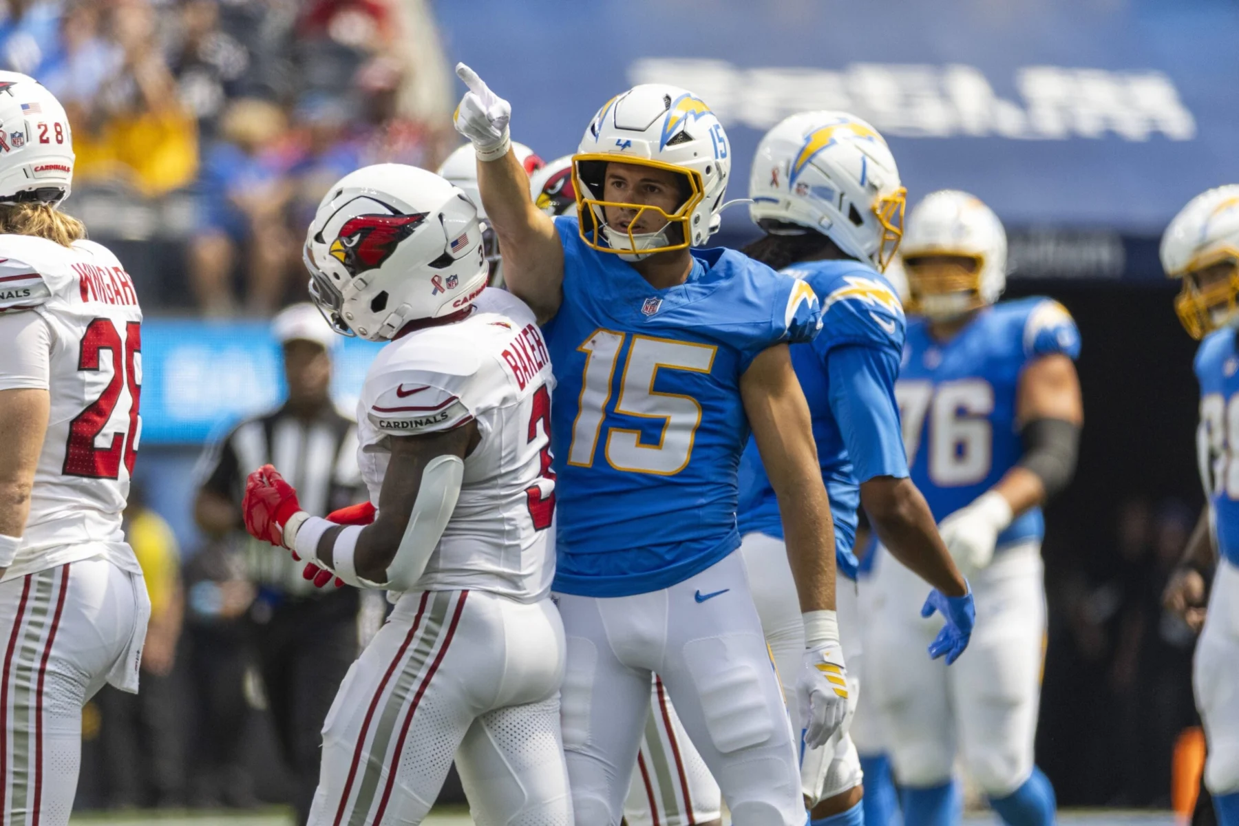 Ladd McConkey - Ein Footballspieler in einem blauen Chargers-Trikot zeigt nach oben, während er während eines Spiels neben McConkey in einem weißen Trikot steht. Alt-Text wurde KI-generiert.