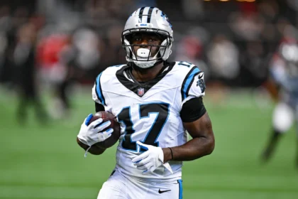 Xavier Legette - Ein Footballspieler in einem weißen Trikot der Carolina Panthers hält einen Football in der Hand, während er über das Spielfeld läuft, nachdem die Panthers Legette im Rahmen einer neuen Strategie eingesetzt haben. Alt-Text wurde KI-generiert.