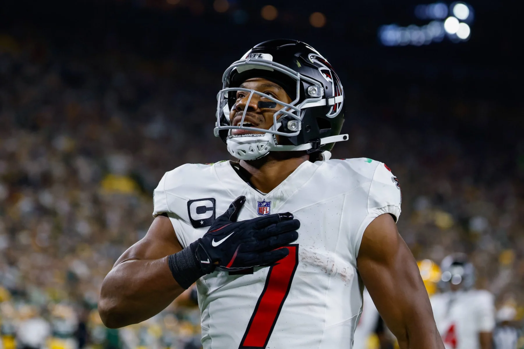 Bijan Robinson - Ein Spieler der Atlanta Falcons im Trikot mit der Nummer 7, der während des „Monday Night Football“ die Hand auf das Herz legt. Alt-Text wurde KI-generiert.