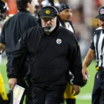 Mike McCarthy, Cheftrainer der Pittsburgh Steelers, trägt während eines Footballspiels ein Headset und eine schwarze Jacke.