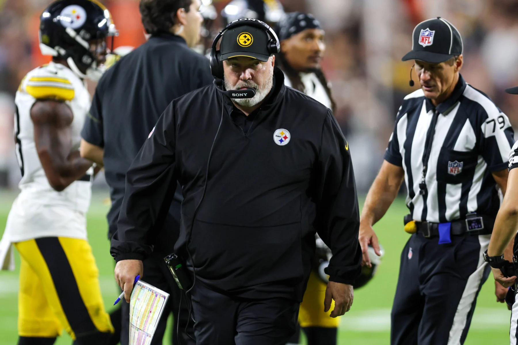 Mike McCarthy, Cheftrainer der Pittsburgh Steelers, trägt während eines Footballspiels ein Headset und eine schwarze Jacke.