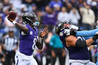 Lamar Jackson, Quarterback der Baltimore Ravens, bereitet sich während des „Sunday Night Football“-Spiels auf einen Pass vor, während ein Teamkollege einen Spieler der Tennessee Titans blockt. Alt-Text wurde KI-generiert.