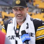 Aaron Rodgers - Ein Spieler der Pittsburgh Steelers in einem schwarz-gelben Trikot und einer Kappe spricht in ein CBS-Sports-Mikrofon.