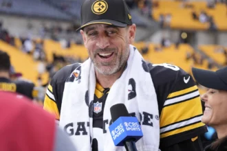 Aaron Rodgers - Ein Spieler der Pittsburgh Steelers in einem schwarz-gelben Trikot und einer Kappe spricht in ein CBS-Sports-Mikrofon.