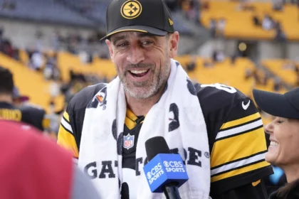 Aaron Rodgers - Ein Spieler der Pittsburgh Steelers in einem schwarz-gelben Trikot und einer Kappe spricht in ein CBS-Sports-Mikrofon.