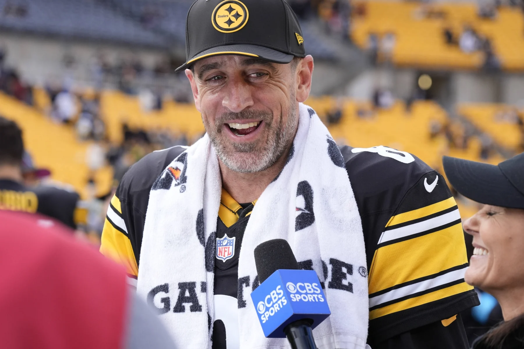Aaron Rodgers - Ein Spieler der Pittsburgh Steelers in einem schwarz-gelben Trikot und einer Kappe spricht in ein CBS-Sports-Mikrofon.