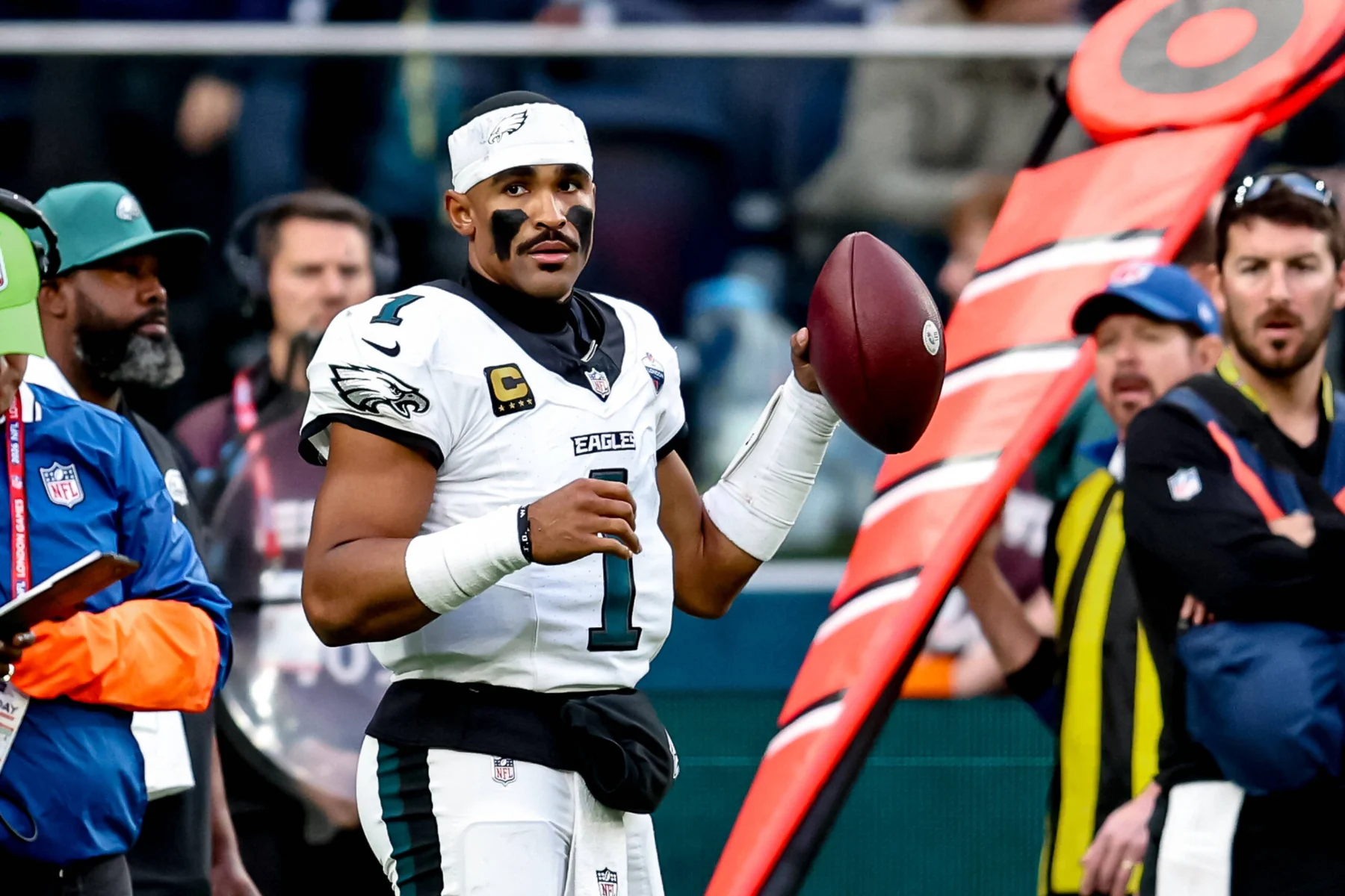 Jalen Hurts steht in seinem Trikot der Philadelphia Eagles mit einem Football an der Seitenlinie.