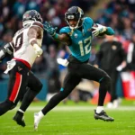Travis Hunter - Ein Spieler der Jacksonville Jaguars in einem türkisfarbenen Trikot läuft mit dem Ball und wird von einem Verteidiger der Houston Texans verfolgt.