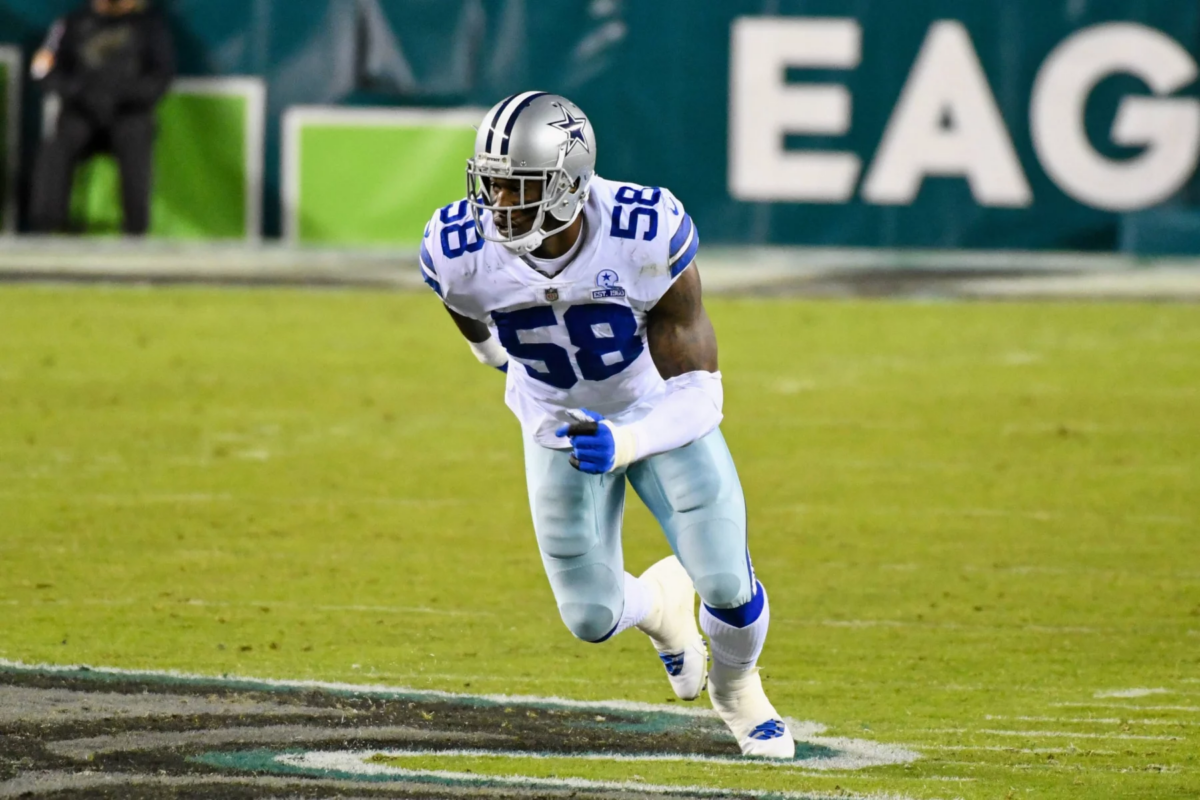 Der Footballspieler der Dallas Cowboys, Aldon Smith, mit der Rückennummer 58, rennt während eines Spiels über das Spielfeld, wobei im Hintergrund ein Teil des Wortes „EAGLES“ zu sehen ist. Alt-Text wurde KI-generiert.