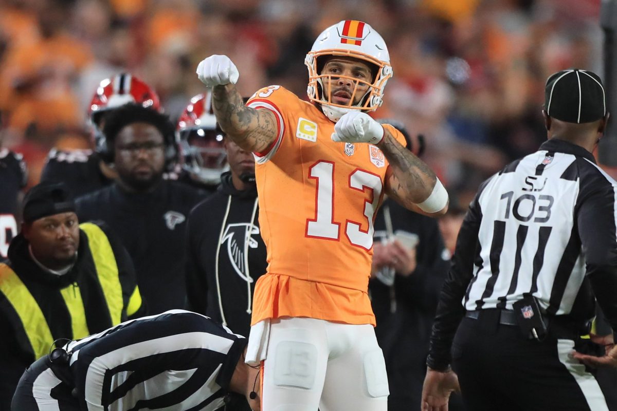 Footballspieler Mike Evans in orangefarbenem Trikot mit Nummer 13 feiert Geste, Schiedsrichter und Zuschauer im Hintergrund