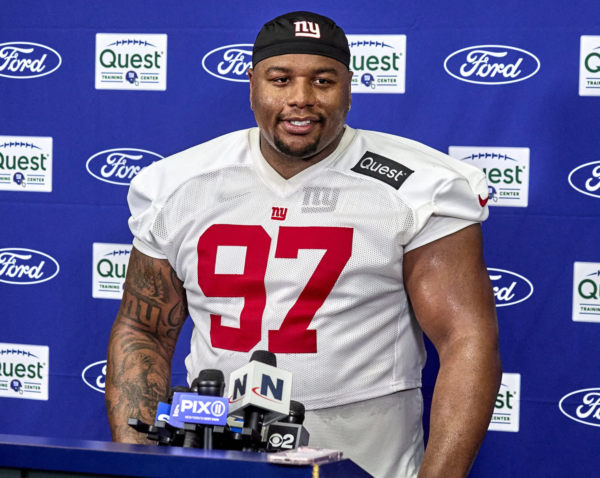 Der Spieler der New York Giants, Dexter Lawrence (Nummer 97), steht während einer Presseveranstaltung an einem Podium mit Mikrofonen und diskutiert möglicherweise über die Spielzüge des Teams im Vorfeld des NFL Draft 2026. Alt-Text wurde KI-generiert.