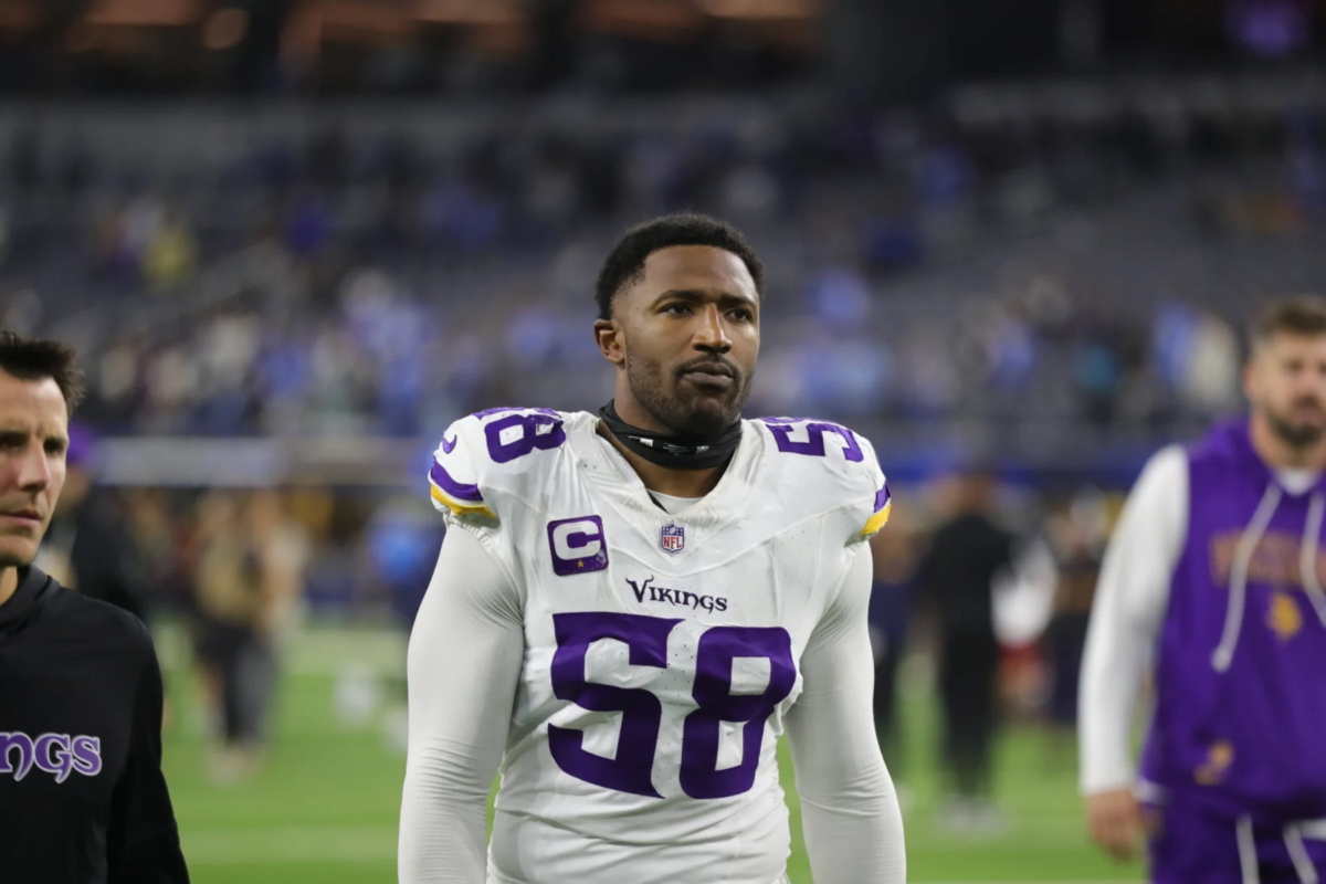 Jonathan Greenard, der ein weißes Minnesota Vikings-Trikot mit der Nummer 58 trägt, steht auf dem Spielfeld und blickt nach vorne, während im Hintergrund weitere Personen zu sehen sind. Der entschlossene Wikinger beobachtet die Szene, während das Spiel gegen die Eagles immer intensiver wird. Alt-Text wurde KI-generiert.