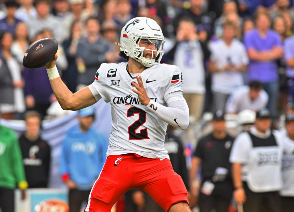 Der Footballspieler der Cincinnati Bearcats, Brendan Sorsby (weißes Trikot mit der Nummer 2), bereitet sich während eines Spiels auf einen Pass vor, im Hintergrund ist das Publikum zu sehen – ein potenzieller Kandidat für den NFL Supplemental Draft 2026. Alt-Text wurde KI-generiert.