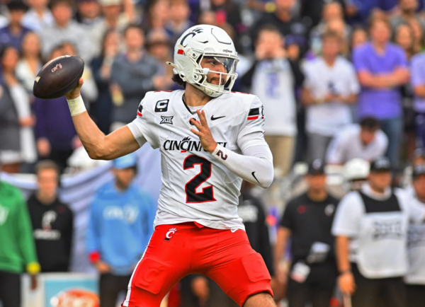 Der Footballspieler der Cincinnati Bearcats, Brendan Sorsby (weißes Trikot mit der Nummer 2), bereitet sich während eines Spiels auf einen Pass vor, im Hintergrund ist das Publikum zu sehen – ein potenzieller Kandidat für den NFL Supplemental Draft 2026. Alt-Text wurde KI-generiert.