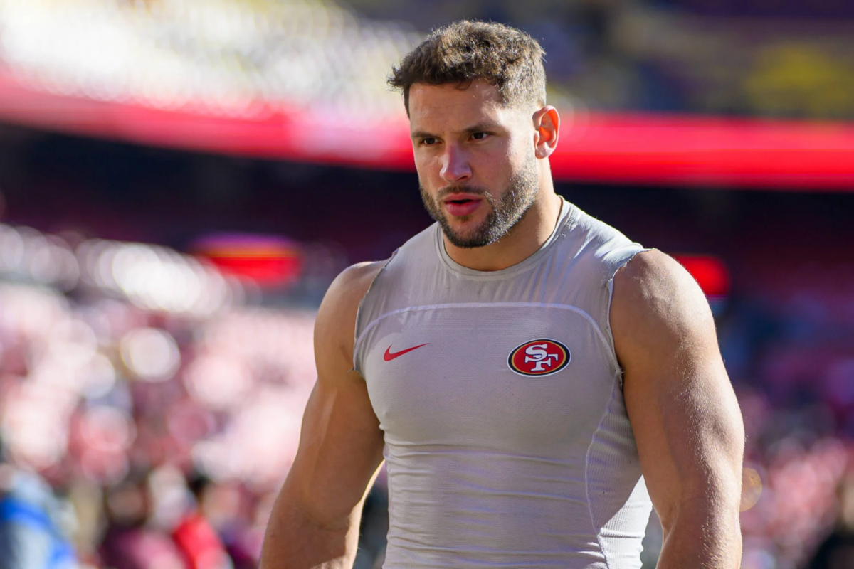Nick Bosa - Ein muskulöser Footballspieler in einem ärmellosen Trikot der San Francisco 49ers steht auf einem Spielfeld, im Hintergrund sind verschwommene Stadionplätze zu sehen – bereit, im Saisonauftakt der 49ers zu dominieren, wenn Bosa spielt. Alt-Text wurde KI-generiert.