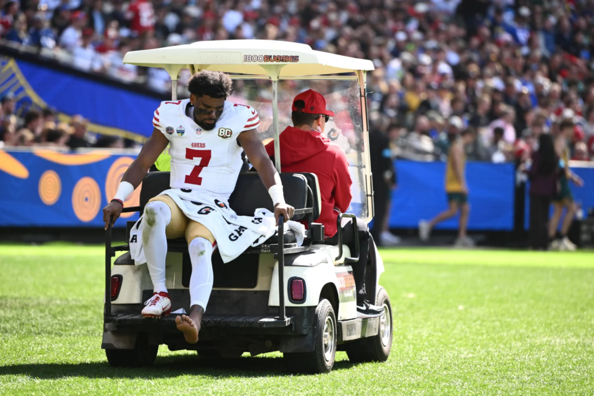 De’Zhaun Stribling - Ein Footballspieler in Spielkleidung, der als Stribling von den 49ers identifiziert wurde, sitzt auf der Ladefläche eines Sanitätswagens, der während eines Spiels vom Spielfeld gefahren wird, nachdem er sich eine Knöchelverletzung zugezogen hat; im Hintergrund ist das Publikum zu sehen. Alt-Text wurde KI-generiert.